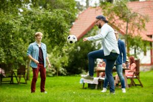 happy friends playing football at summer garden